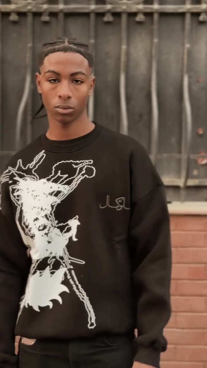 A model in a black Clocal sweatshirt against an iron gate